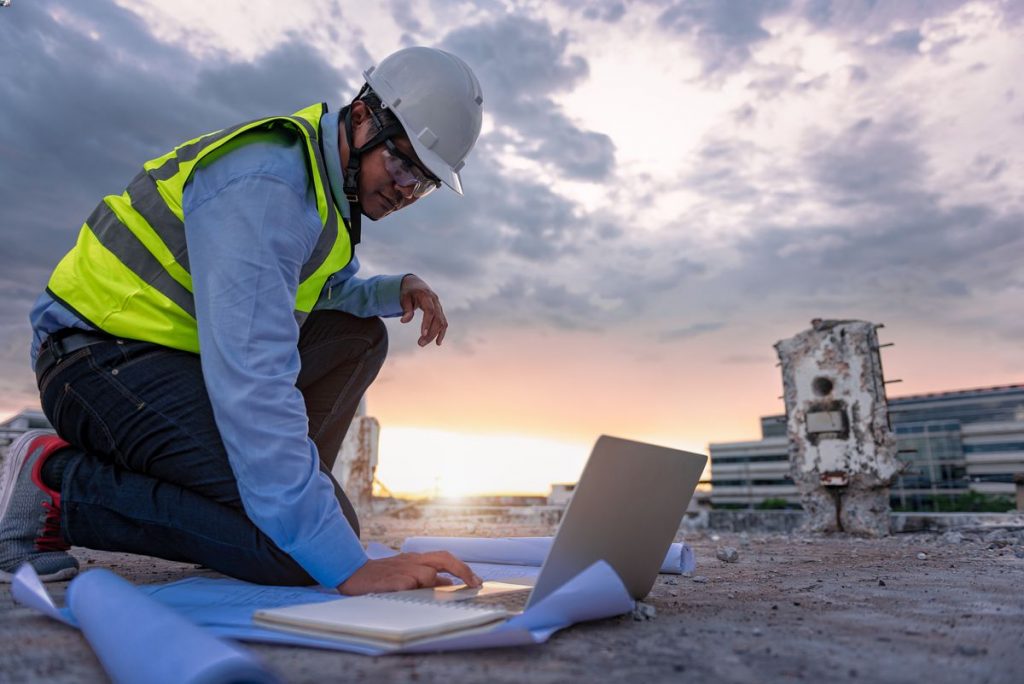 BIM Manager working on a laptop on a construction site.