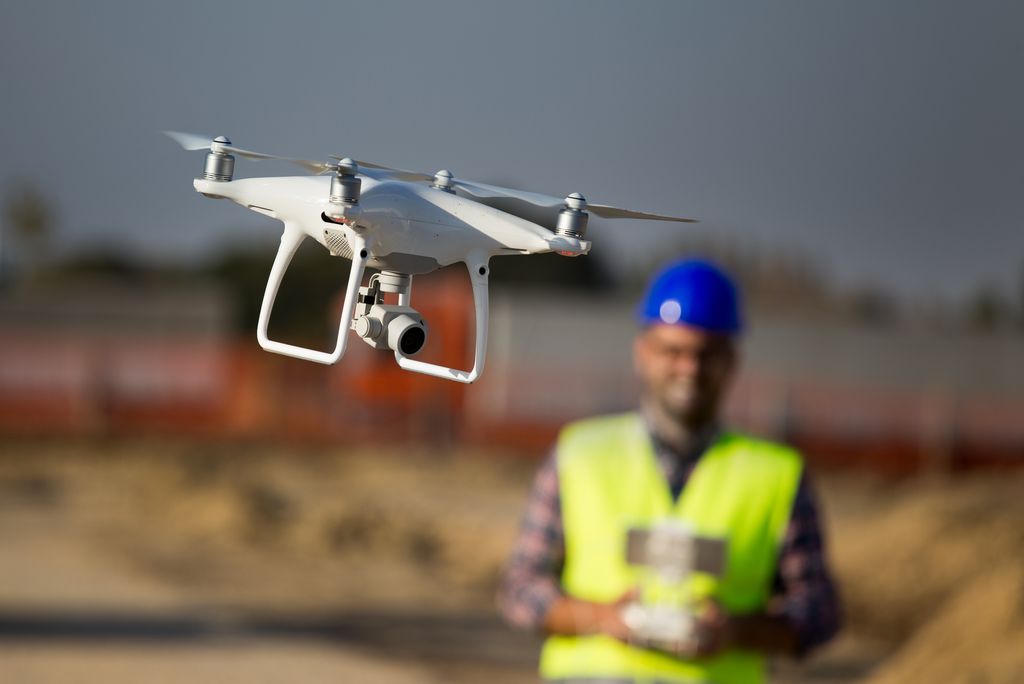 Construction worker using a drone to map out a construction site with reality capture.