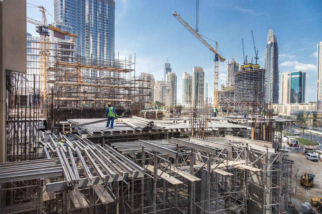 Building work being carried out in Dubai by workers on the site who are directing a crane.