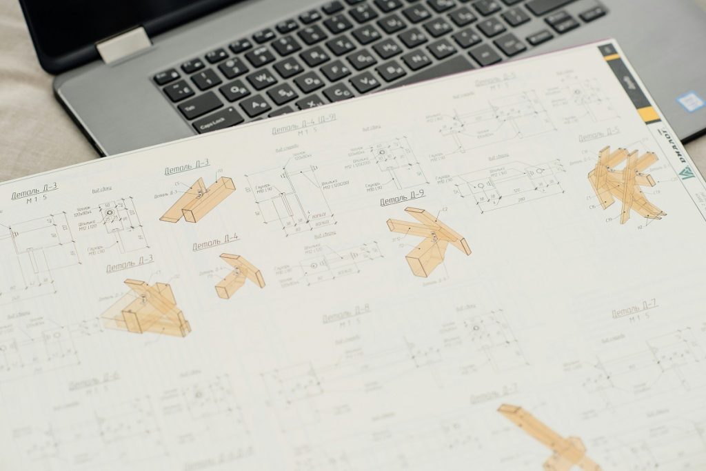 Close-up of an architectural or engineering drawing showing timber assembly components alongside a laptop keyboard