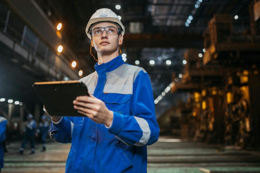 Engineer using mobile tablet in industrial setting for workforce coordination