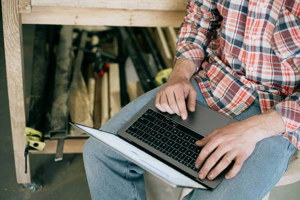 Maintenance worker using a laptop to manage housing operations digitally in a workshop setting