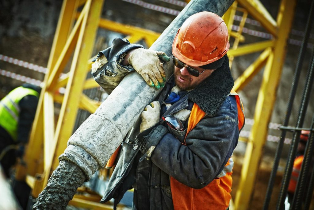 Construction worker using heavy equipment on site during concrete pour