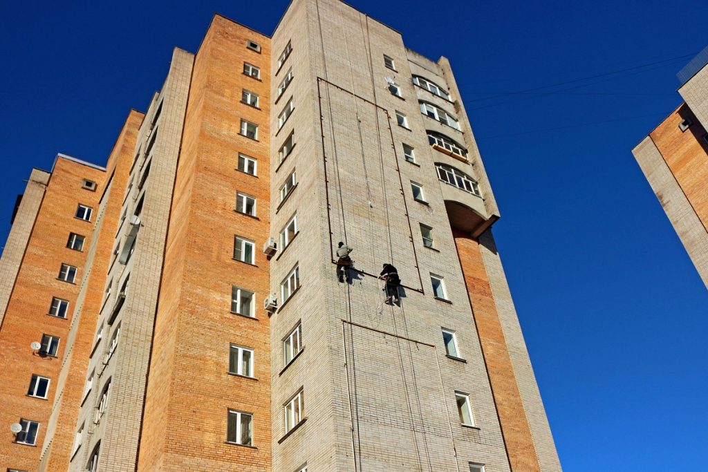 Workers conducting high-rise maintenance on social housing apartment block exterior