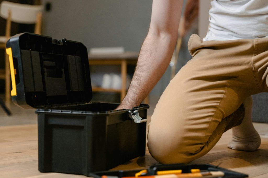 Close-up of maintenance worker reaching into a toolbox during a social housing repair