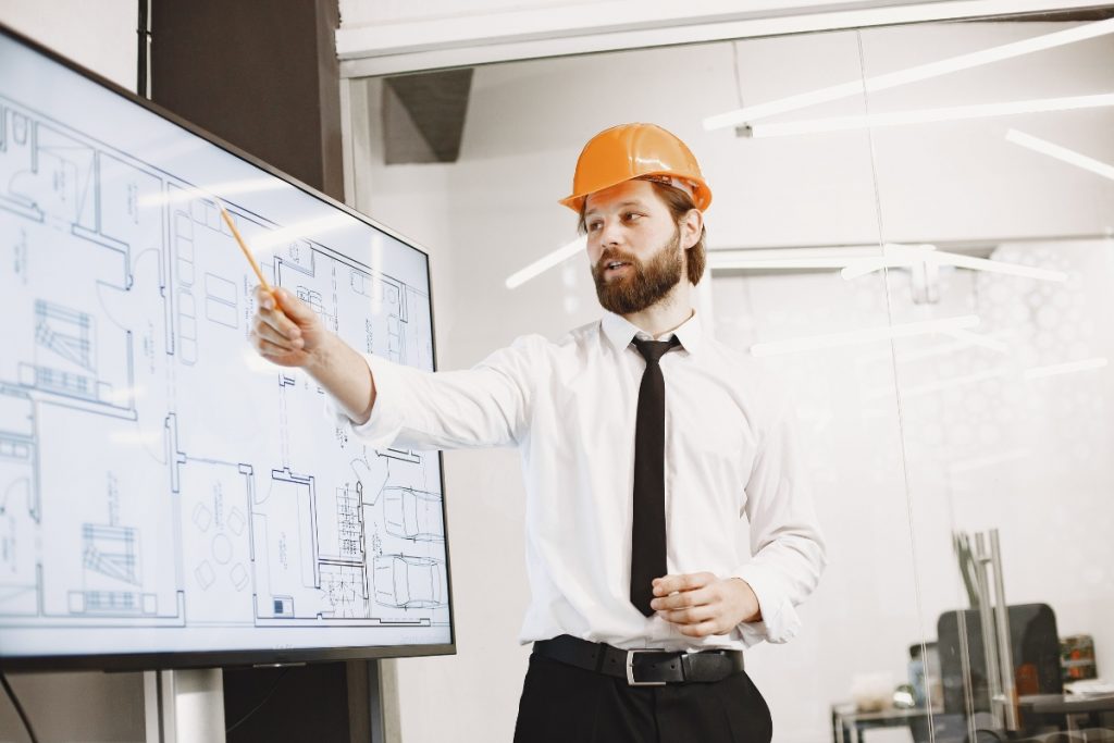 Construction professional leading a BIM coordination meeting using digital building plans to improve collaboration, information management and project delivery.
